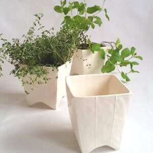 3 Small square ceramic planters with 4 pointed feet. Shown in white with and without potted plants