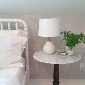 Handmade white ceramic table lamp with white stripes on table, topped with white linen shade