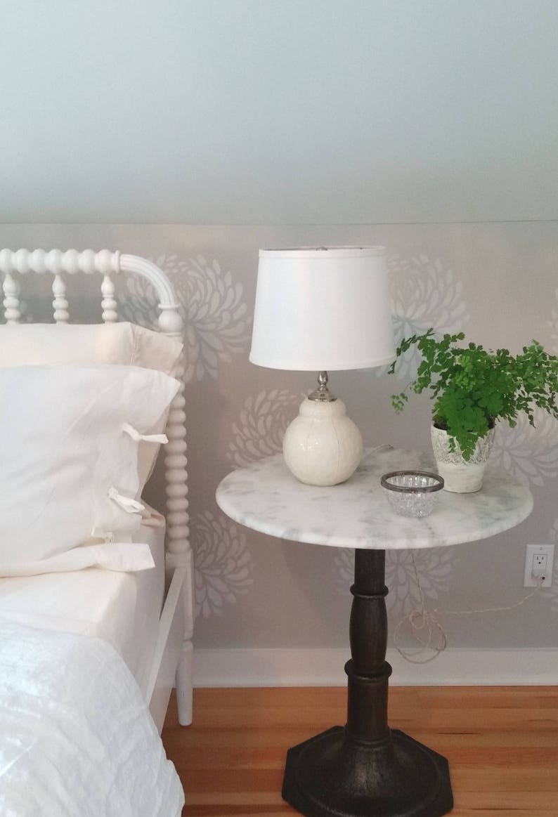 Handmade white ceramic table lamp with white stripes on table, topped with white linen shade