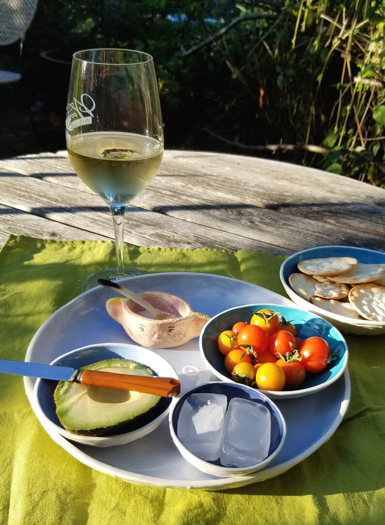 set of 4 nesting bowls in different shades of blue shown in garden setting with food & wine