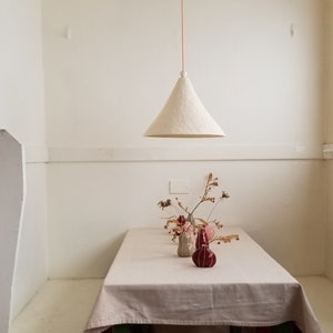 Large, 15" diameter, white cone pendant light with bead detail. Hangs over table. Front view