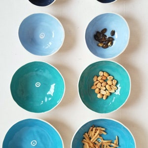 2 sets of 4 nesting bowls in different shades of blue, side by side showing how they look empty and with snacks inside