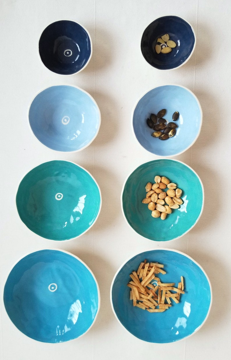 2 sets of 4 nesting bowls in different shades of blue, side by side showing how they look empty and with snacks inside