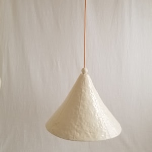 View of large, 15" diameter, white cone pendant light with bead detail. Shows ceiling canopy.
