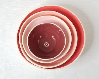 Set of 4 small nesting ceramic dishes in red, pink, peach, & maroon