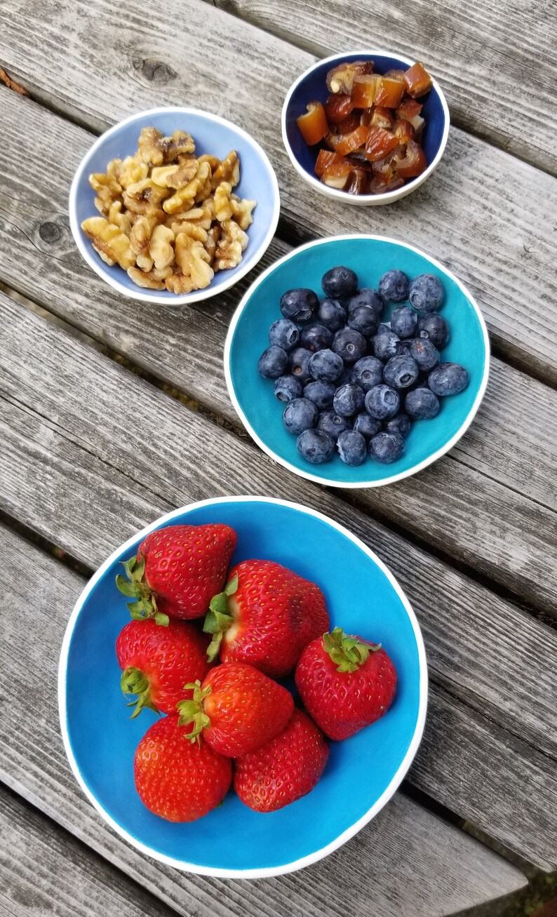 set of 4 nesting bowls in different shades of blue shown with strawberries, blueberries, nuts & dates