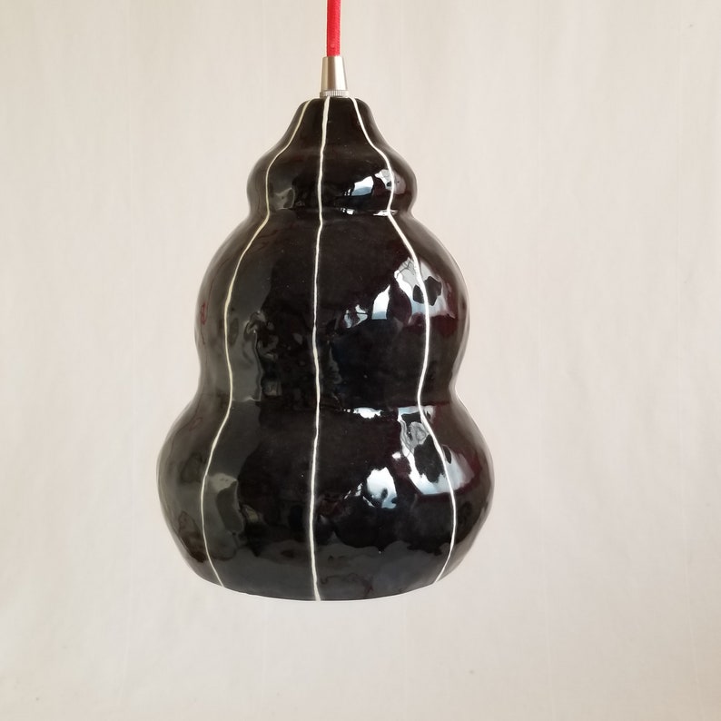 Side view of Black ceramic pendant light with thin white stripes