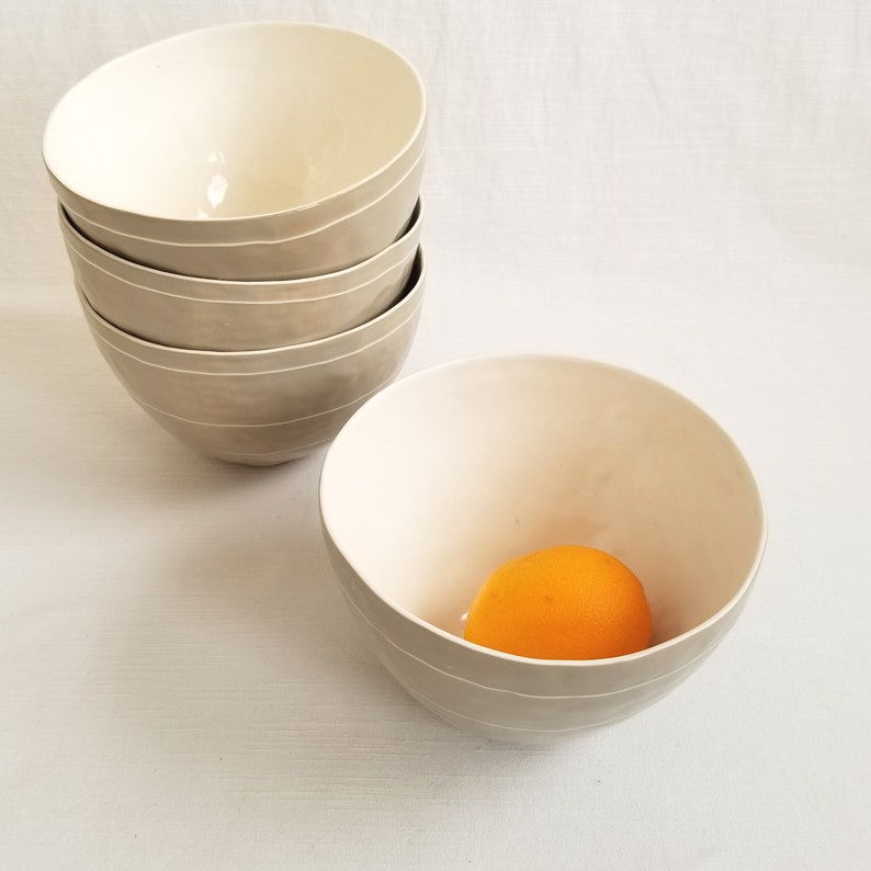 stack of porcelain serving bowls in taupe with thin white stripes. Shown from above