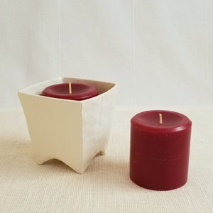small square planter in white used to hold a red pillar candle