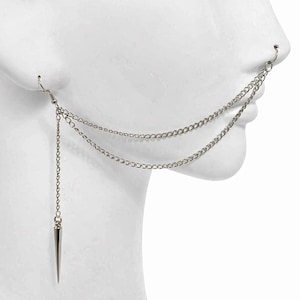 May include: Silver-toned chain ear and nose jewelry. The design features a chain that connects from the ear to the nose, with a dangling spike pendant. The jewelry is shown on a white mannequin head.