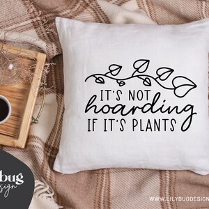 May include: White throw pillow with black text that reads "It's not hoarding if it's plants." The text is surrounded by a vine with leaves.