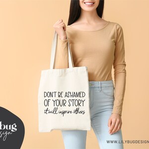 May include: A white tote bag with black text that reads "Don't be ashamed of your story it will inspire others".