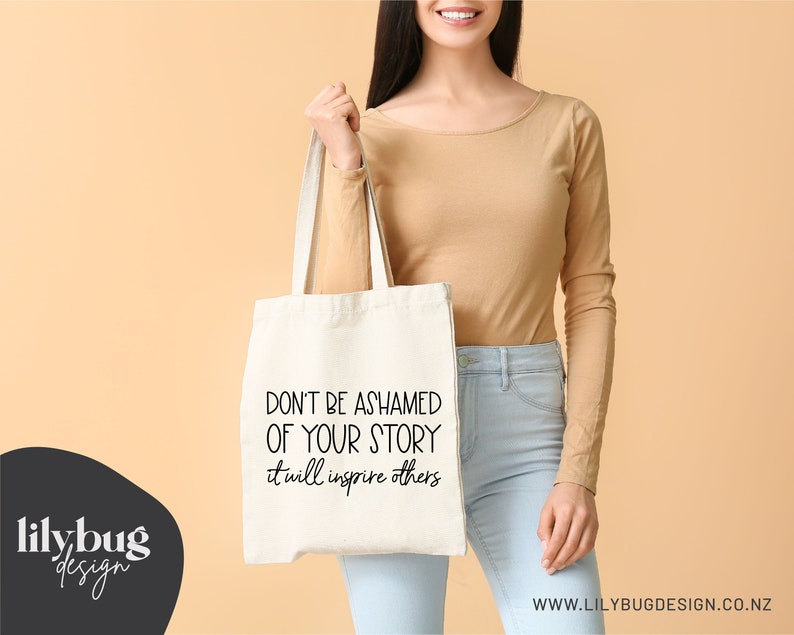 May include: A white tote bag with black text that reads "Don't be ashamed of your story it will inspire others".