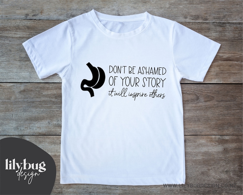 May include: White t-shirt with a black silhouette of a stomach and the text "Don't be ashamed of your story it will inspire others".