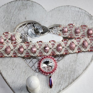 May include: A white and pink beaded choker necklace with a silver clasp and a pink crystal pendant.