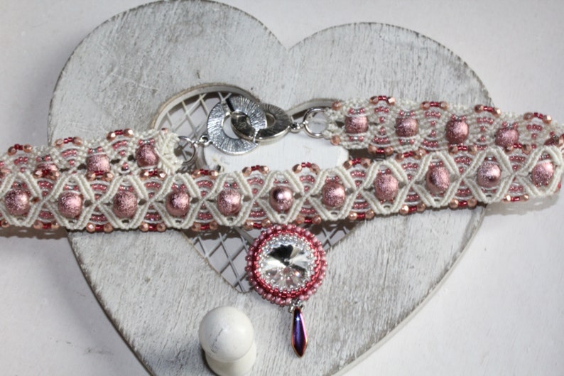 May include: A white and pink beaded choker necklace with a silver clasp and a pink crystal pendant.