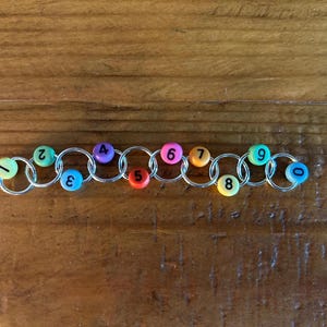 May include: A rainbow-colored chain of linked rings with numbers 1 through 9 printed on each ring.