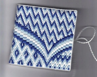 May include: A small, square, blue and white patterned fabric with a white thread attached.