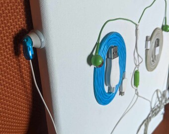 Könnte beinhalten: Eine weiße Leinwand mit verschiedenen Kabeln und Kopfhörern daran befestigt. Die Kabel sind weiß, blau und grün. Die Kopfhörer sind weiß und blau.
