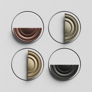 May include: Four decorative wall accents. Each accent features a semi-circular, layered design in a different metallic finish: copper, gold, brass, and black. The semi-circles are set within a gray circular frame against a white textured background.