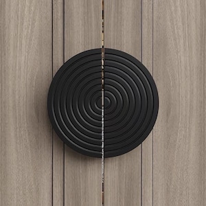 May include: A black circular door handle with concentric circles, mounted on a wood panel.