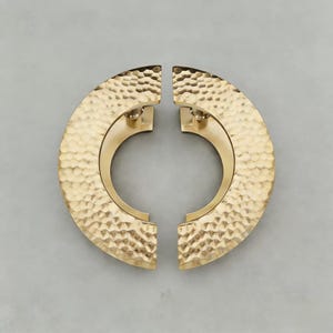 May include: Two matching, half-circle cabinet pulls with a hammered gold finish. Each pull has a semi-circular design with a textured surface and is mounted with two screws. The hardware is designed for easy installation and adds a touch of elegance.