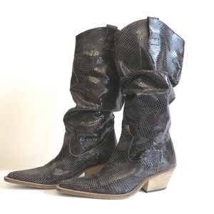 Può includere: Un paio di stivali da cowboy marroni in pelle effetto serpente con punta a punta e tacco basso.