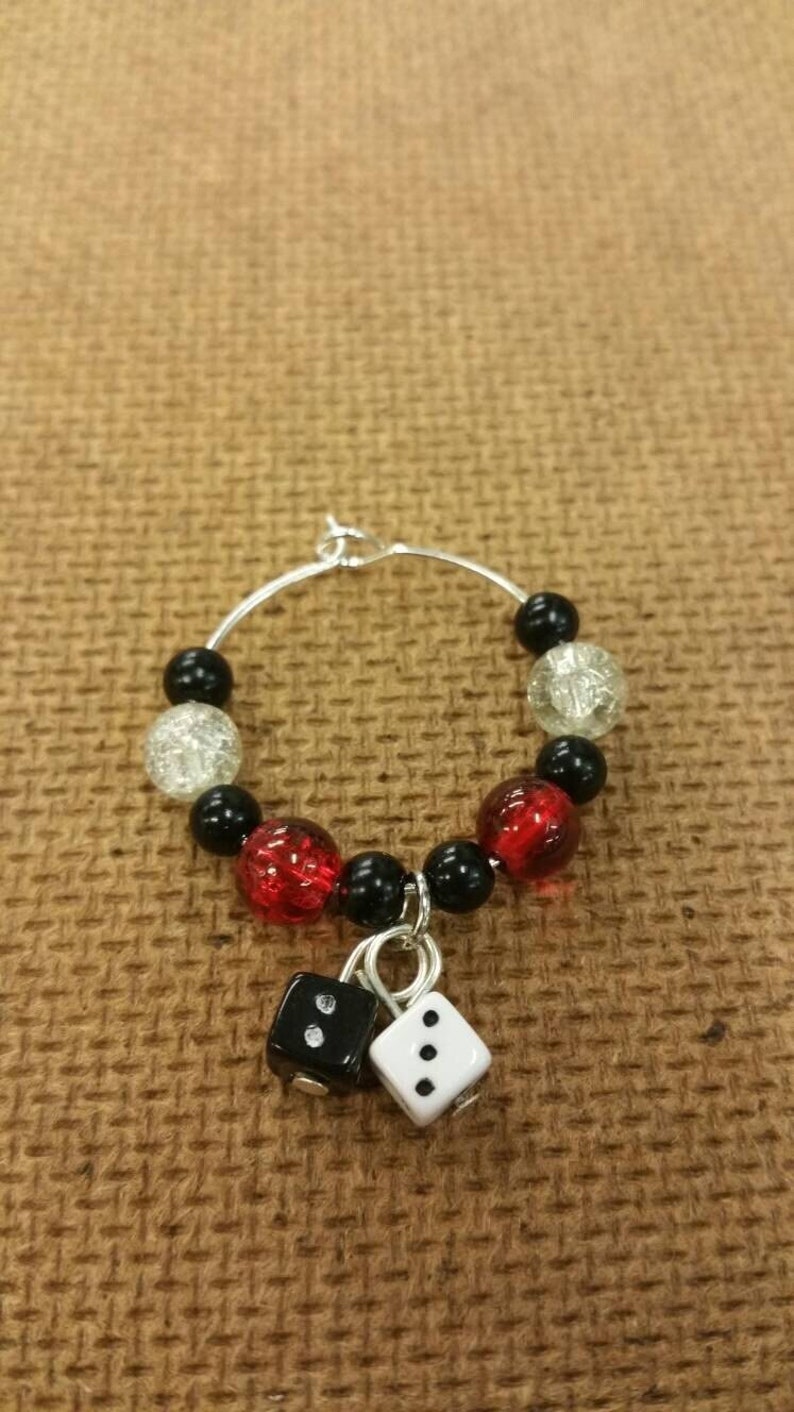 May include: A silver wine glass charm with black, red, and white beads and two dice charms. One die is black with white dots and the other is white with black dots.