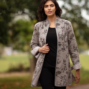 May include: A grey quilted jacket with a floral print. The jacket has a mandarin collar and long sleeves.