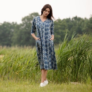 May include: A blue and white floral print midi dress with a V-neckline and 3/4 sleeves. The dress has a relaxed fit and is made of a soft, comfortable fabric.