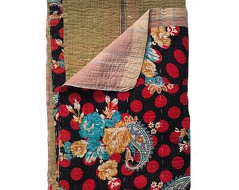 May include: A kantha quilt with a black background and red polka dots. The quilt is decorated with a floral pattern in shades of blue, yellow, and green. The quilt is folded in half, revealing a light brown fabric on the inside.