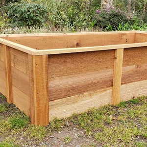 以下が含まれることがあります： セダー板で作られた長方形のウッド製の高床式菜園。ベッドは芝生の上に置かれています