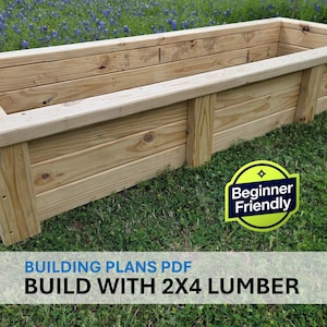Può includere: Una fioriera rettangolare in legno chiaro. La scatola è costruita con assi orizzontali e supporti verticali, appoggiata su una superficie erbosa. L'immagine include il testo "BUILD WITH 2X4 LUMBER".