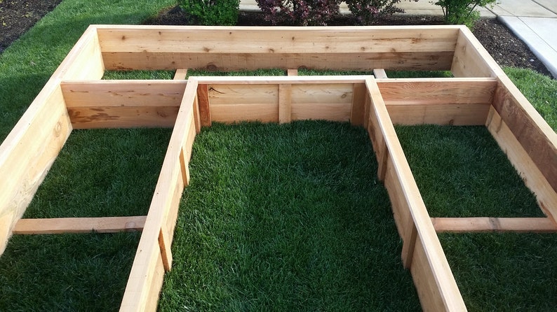 May include: A wooden raised garden bed with three sections. The bed is filled with green grass.