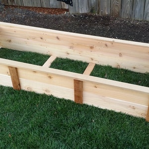 May include: A wooden raised garden bed with a natural wood finish. The bed is empty and ready for planting.