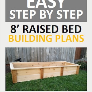 May include: A wooden raised garden bed, 8 feet long, made of cedar planks. The bed is sitting on a green lawn in front of a wooden fence. The text "EASY STEP BY STEP 8' RAISED BED BUILDING PLANS STEWART LANDING CO" is displayed on the image.