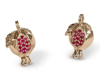 May include: A pair of gold-tone earrings shaped like pomegranates with red crystal accents.