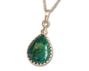 May include: A gold chain necklace with a teardrop-shaped pendant featuring a green gemstone.