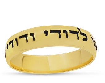 Könnte beinhalten: Ein goldener Ring mit der hebräischen Inschrift "Gesegnet seist du" in schwarzen Buchstaben.