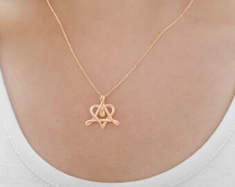 Puede incluir: Un collar de oro rosa con un colgante en forma de corazón que presenta la letra A entrelazada dentro del corazón.