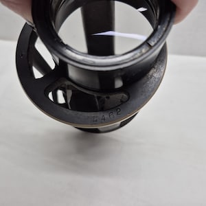 May include: A black circular optical lens component featuring a metal frame with a series of cutouts. The outer edge of the frame is stamped with the number 4462. The lens is clear and circular, set within a cylindrical black housing structure.