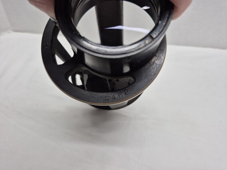 May include: A black circular optical lens component featuring a metal frame with a series of cutouts. The outer edge of the frame is stamped with the number 4462. The lens is clear and circular, set within a cylindrical black housing structure.