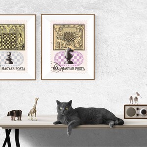 Puede incluir: Dos sellos postales vintage enmarcados con piezas y tableros de ajedrez. Los sellos están en marcos marrones y están montados en una pared blanca. Un gato gris y figuras decorativas están sobre una mesa de madera.