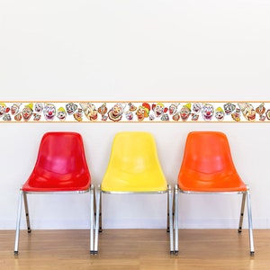 May include: A decorative clown-themed wall border with a repeating pattern of colorful clown faces. Below, three plastic chairs in red, yellow, and orange stand against a white wall. The chairs have silver legs and are arranged in a row.