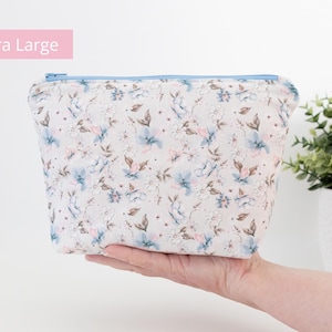 Extra large floral zip pouch held in one hand beside a potted plant, labelled Extra Large.