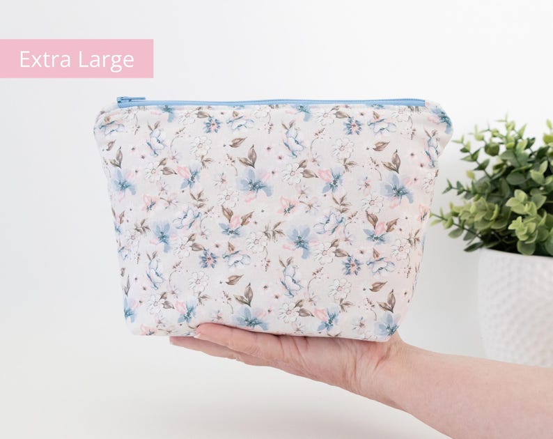 Extra large floral zip pouch held in one hand beside a potted plant, labelled Extra Large.
