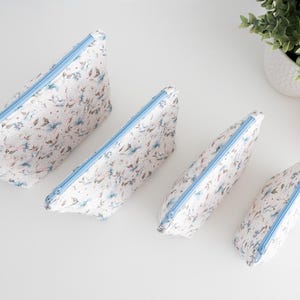 Top-down view of all four zip pouch sizes in matching floral fabric, showing the full size range.