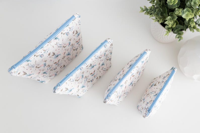 Top-down view of all four zip pouch sizes in matching floral fabric, showing the full size range.