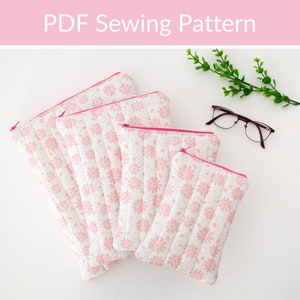 May include: Four pink zippered pouches with a floral pattern. The pouches are nested inside each other, with the largest pouch at the bottom and the smallest pouch at the top. The pouches are made of a quilted fabric.
