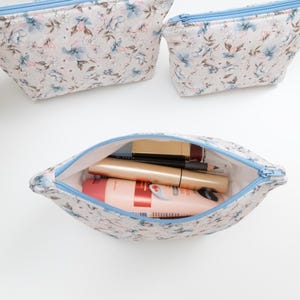 Floral zip pouch opened and filled with makeup and lip products, showing everyday use and size.